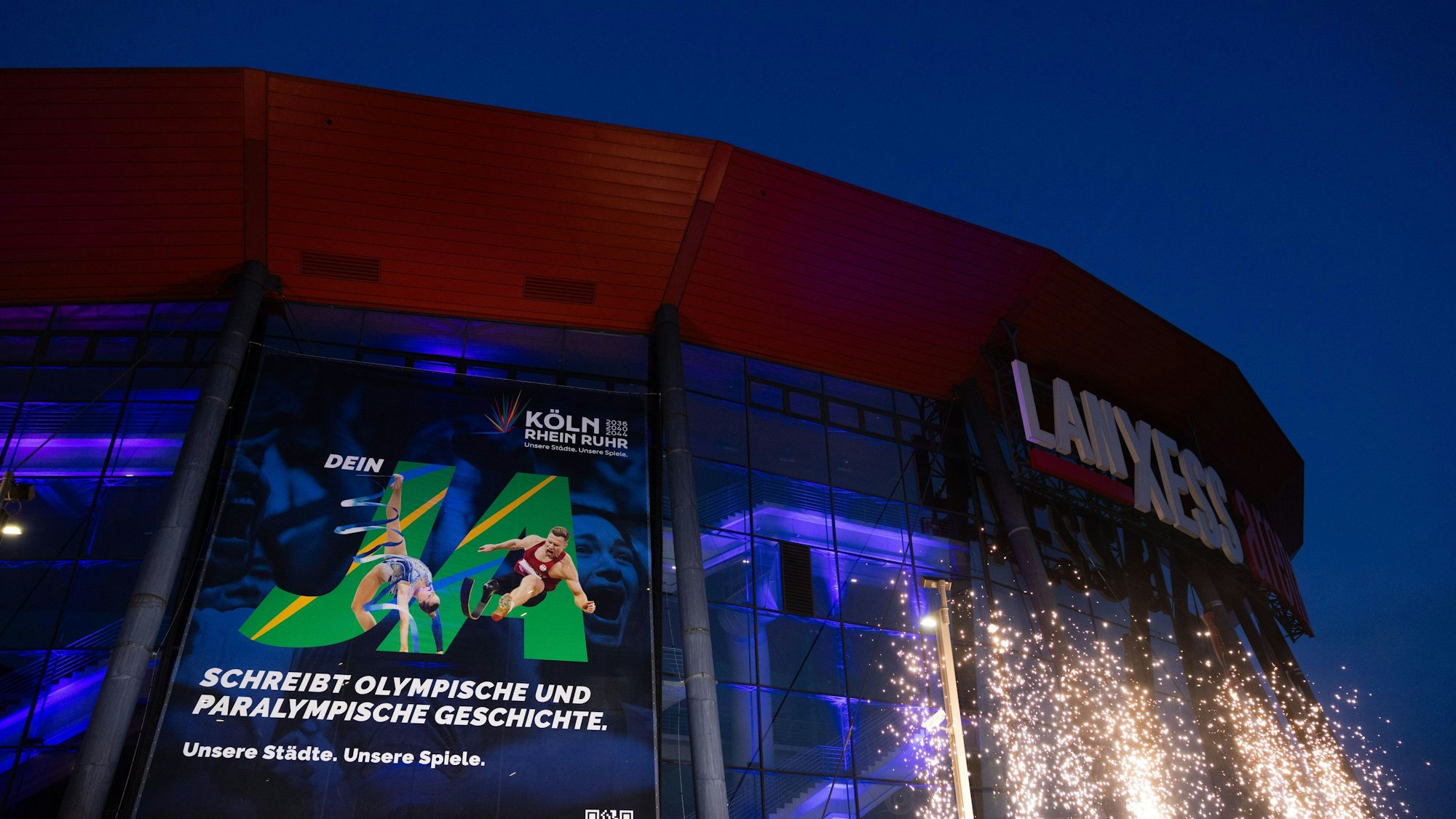 Ein Plakat mit dem Schriftzug „Ja“ hängt beim Start der Kampagne für die Bewerbung Köln-Rhein-Ruhr um Olympische und Paralympische Spiele an der Lanxess-Arena.
