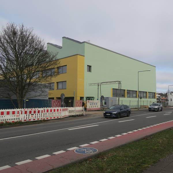 An einer großen Kreuzung steht ein grün-gelbes Schulgebäude.