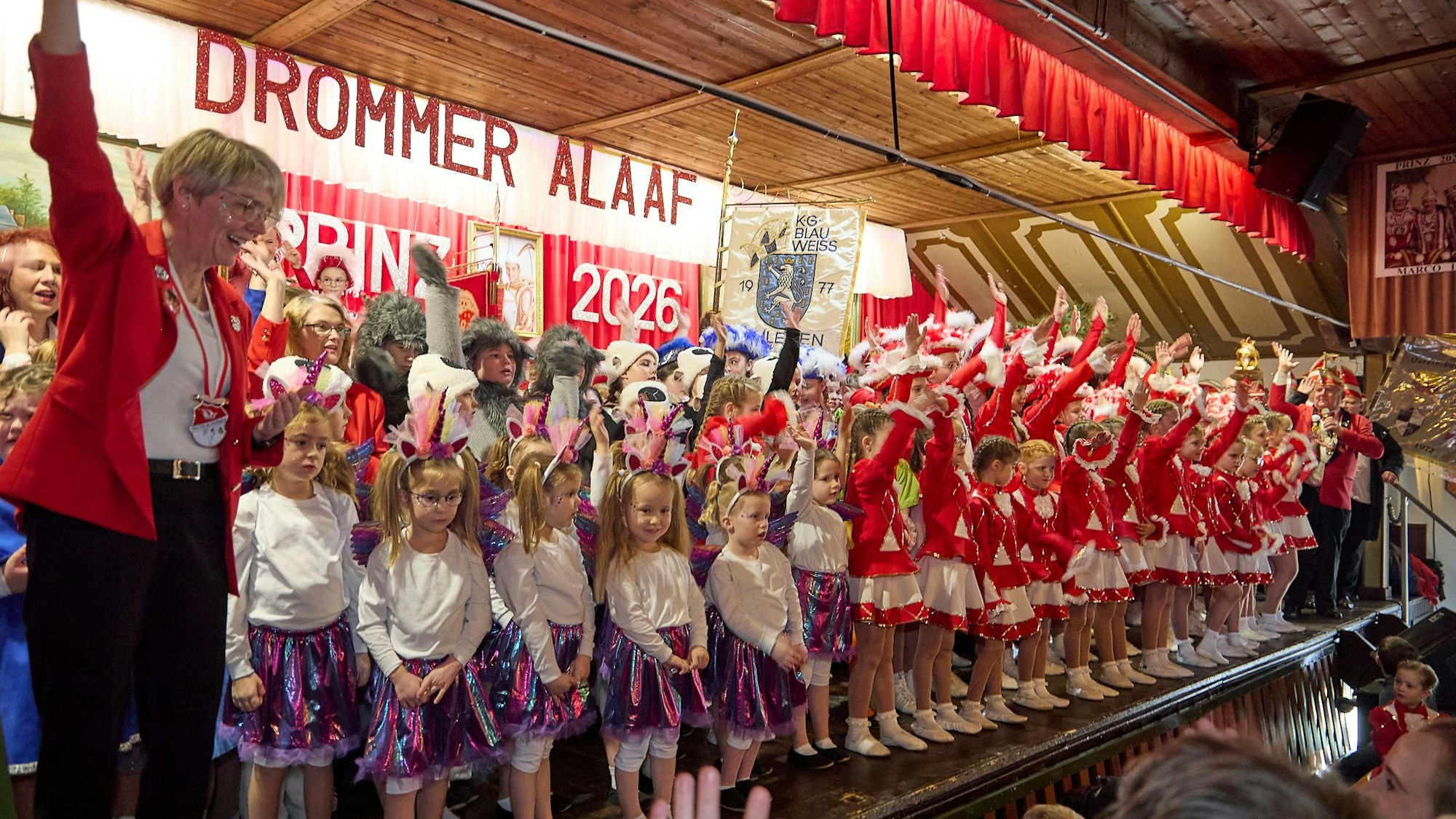 Auf einer Bühne stehen kostümierte Kinder und Erwachsene eng beieinander.