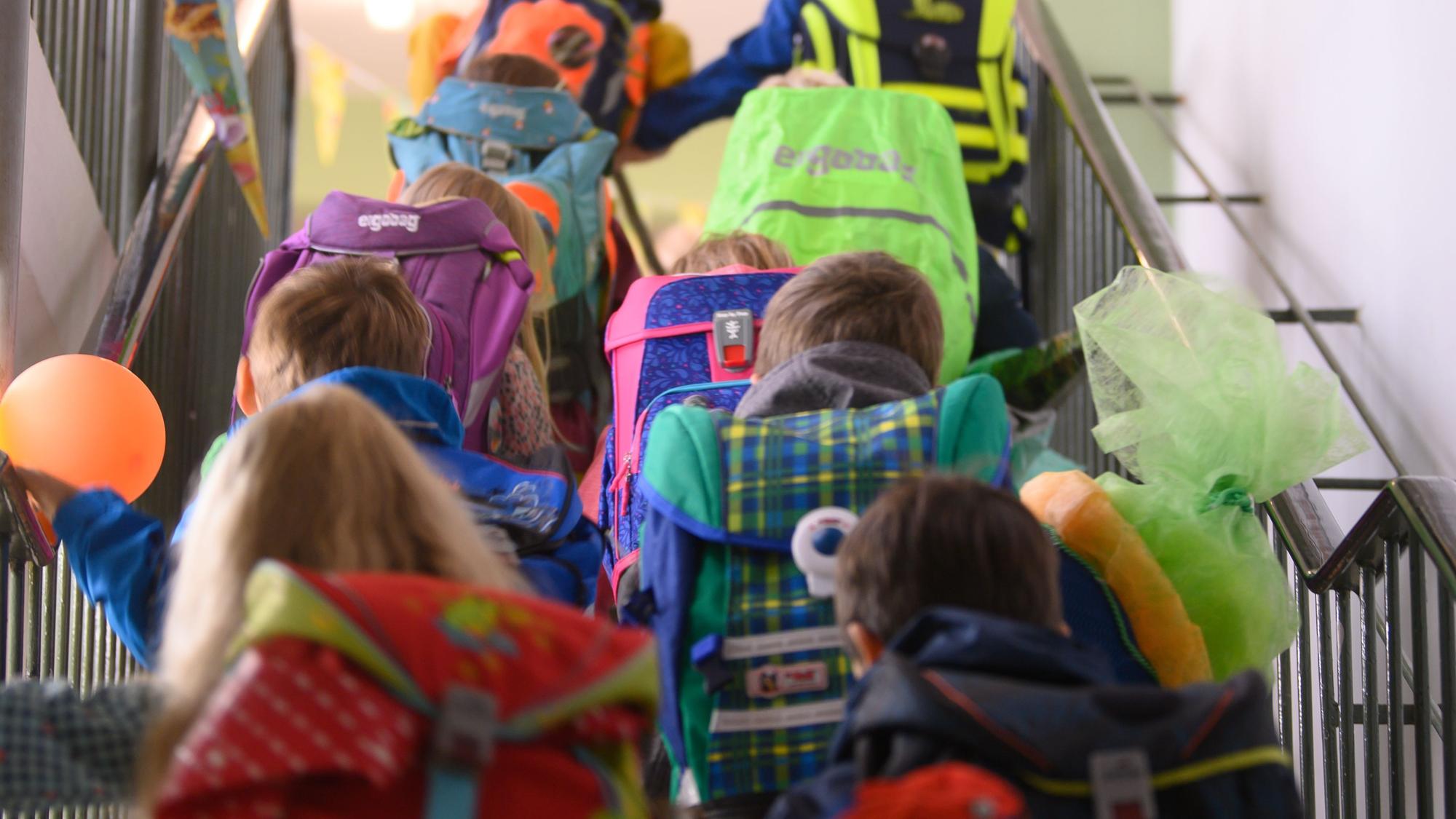 Grundschüler einer ersten Klasse begeben sich an ihrem ersten Schultag durchs Treppenhaus der Schule in ihr Klassenzimmer.
