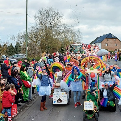 Eine als Regenbögen und Wolken kostümierte Gruppe läuft im Ripsdorfer Zug mit und jubelt den Jecken am Straßenrand zu.