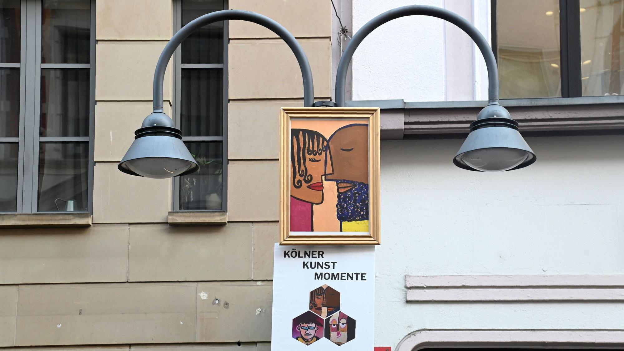 20.01.2026 Köln. "Kölner Kunst Momente": Mit Moderator Thomas Hackenberg (alias TThomas Von Klettenberg ), Jean Nejadi (weiße Jacke ) und Lucie Albrecht . Kunstwerke (Fratzen) von mehreren Künstlern auf A1-Plakaten werden an Laternenkronen auf der Ehrenstraße angebracht. Initiator ist Parfümerie Möltgen auf der Ehrenstraße. Foto: Alexander Schwaiger
