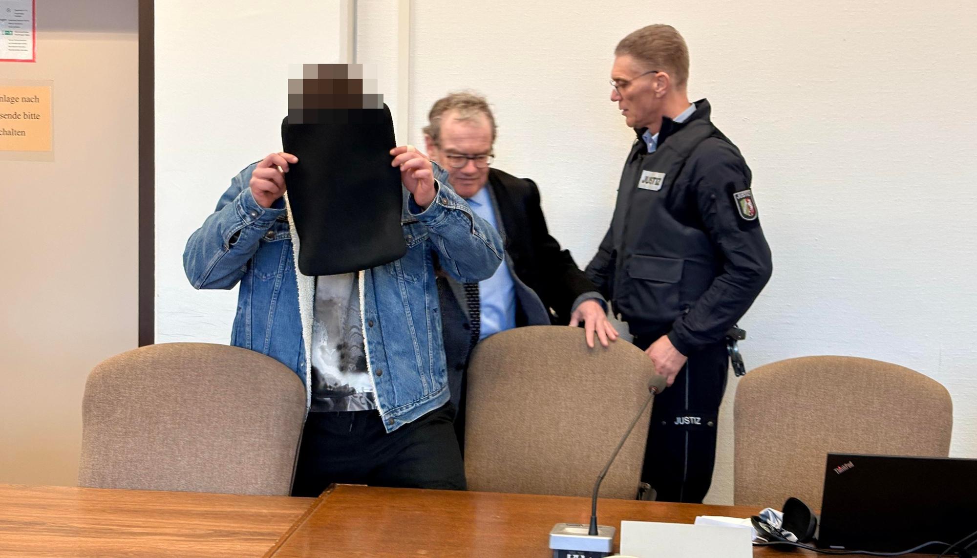 Der Angeklagte mit seinem Verteidiger Lukas Pieplow und einem Wachtmeister beim Prozessauftakt im Kölner Landgericht