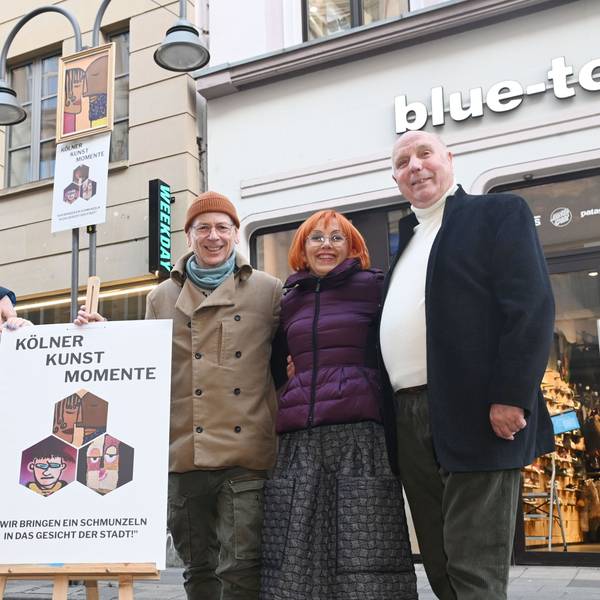 Aktion „Kölner Kunst Momente“ auf der Ehrenstraße: Mit Moderator Thomas Hackenberg (m.) ("Quiz Taxi") alias Thomas von Klettenberg, Kurator Roderik Helms (l.), Jean Nejadi (2.v.l. ) und Künstlerin Lucie Albrecht (2.v.r.) und Peter Möltgen von der Parfümerie Möltgen. Bunte Gesichter, auf A1-Plakate gedruckt, werden an Laternenkronen auf der Ehrenstraße angebracht.
