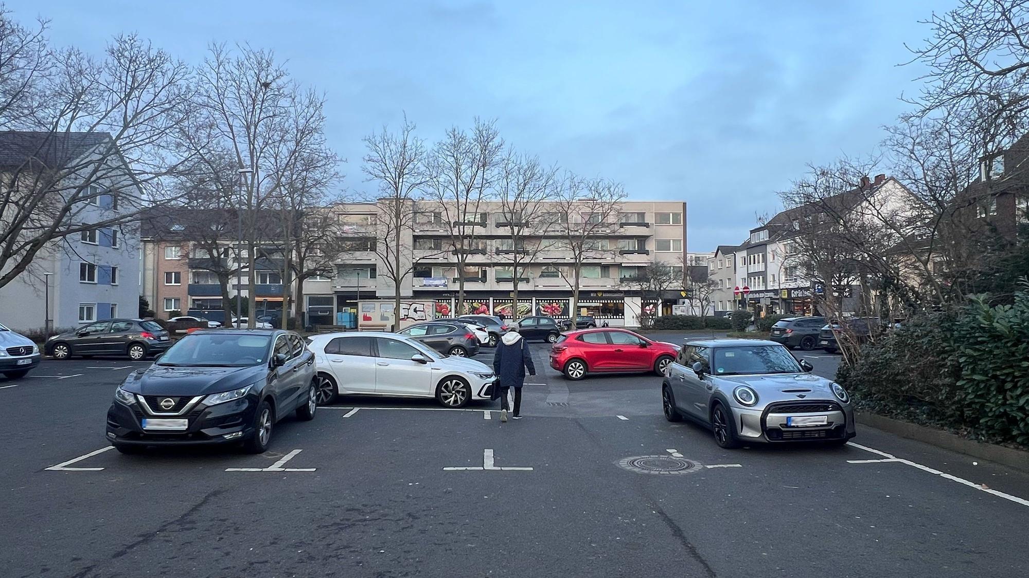 Auf einem Parkplatz sind verstreut Autos abgestellt.