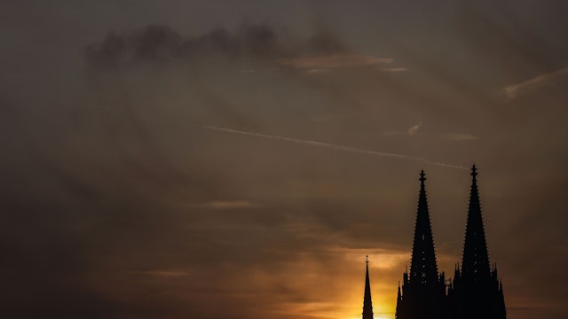 Die Sonne geht am Abend in Köln bei Schleierwolken hinter dem Dom unter.