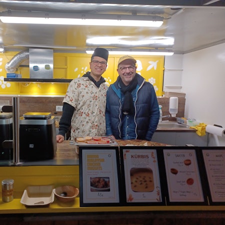 Zwei Männer stehen hinter der Verkaufstheke eines Imbisses.