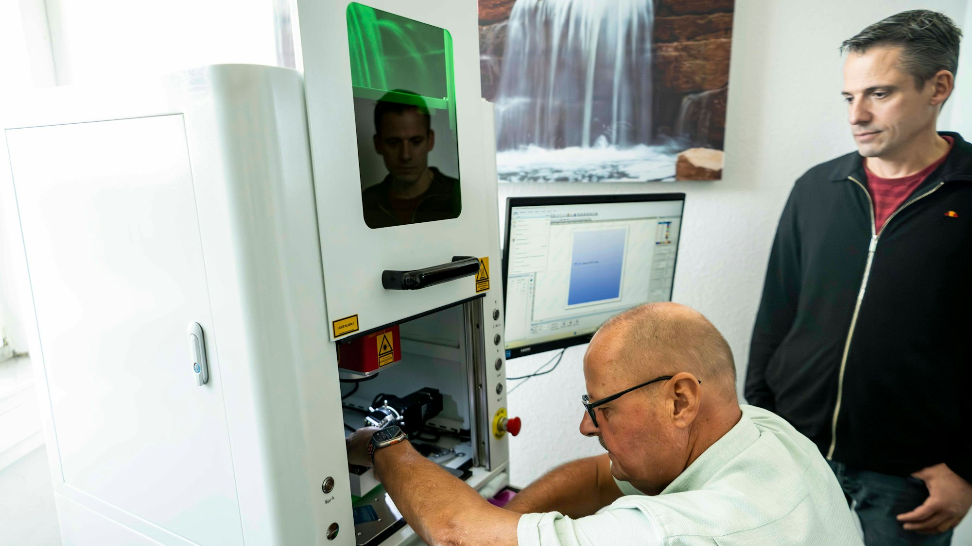 Walter Peter (l.) schaut in das Innere einer Maschine. Neben ihm steht Pascal Korte und schaut ihm über die Schulter.
