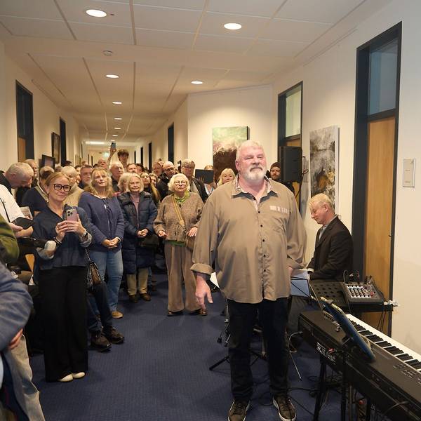 Viele Gäste stehen in einem Korridor das Mechernicher Rathauses. An den Wänden hängen Bilder. Im Vordergrund sitzt ein Mann an einem elektronischen Piano.