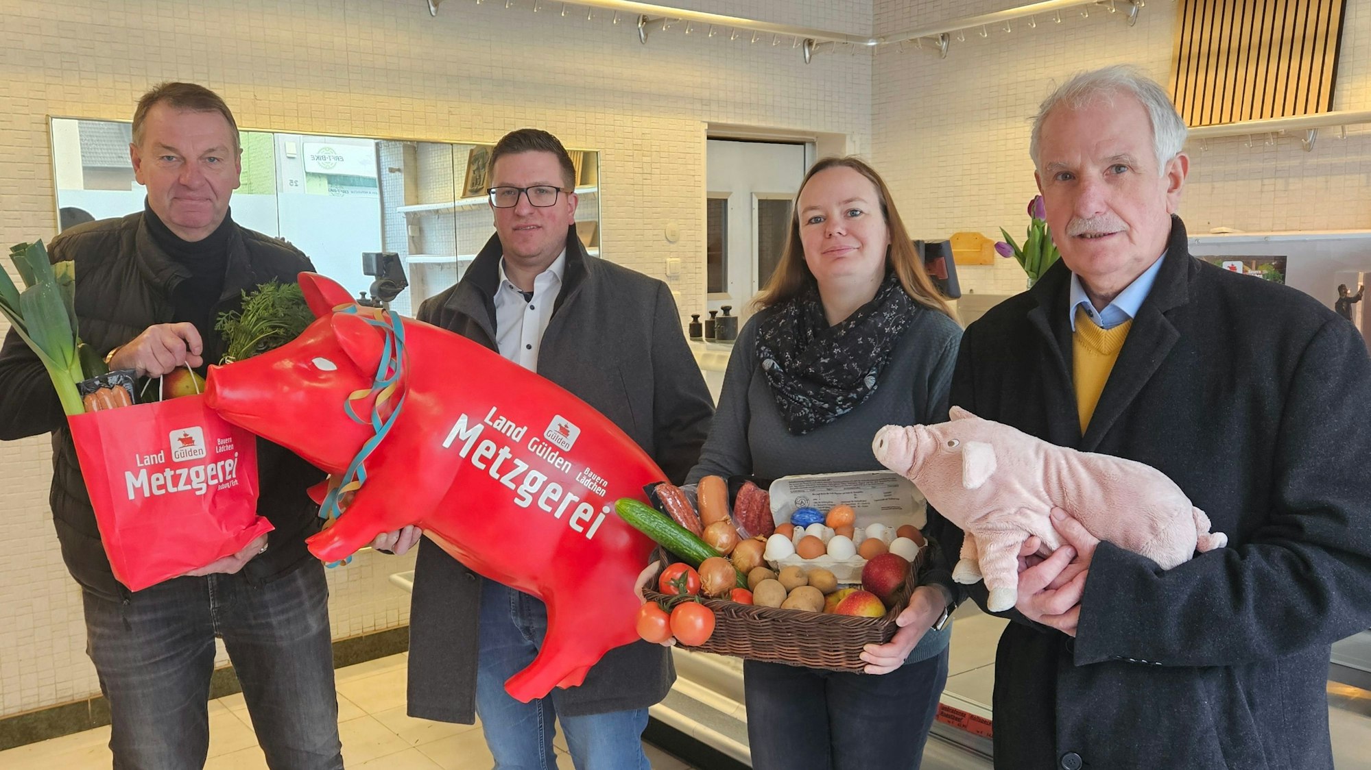 Zu sehen sind drei Männer und einer Frau, die Produkte eines Hofladens halten.