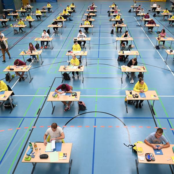 Schüler und Schülerinnen sitzen in einer Sporthalle und schreiben eine Abiturprüfung.