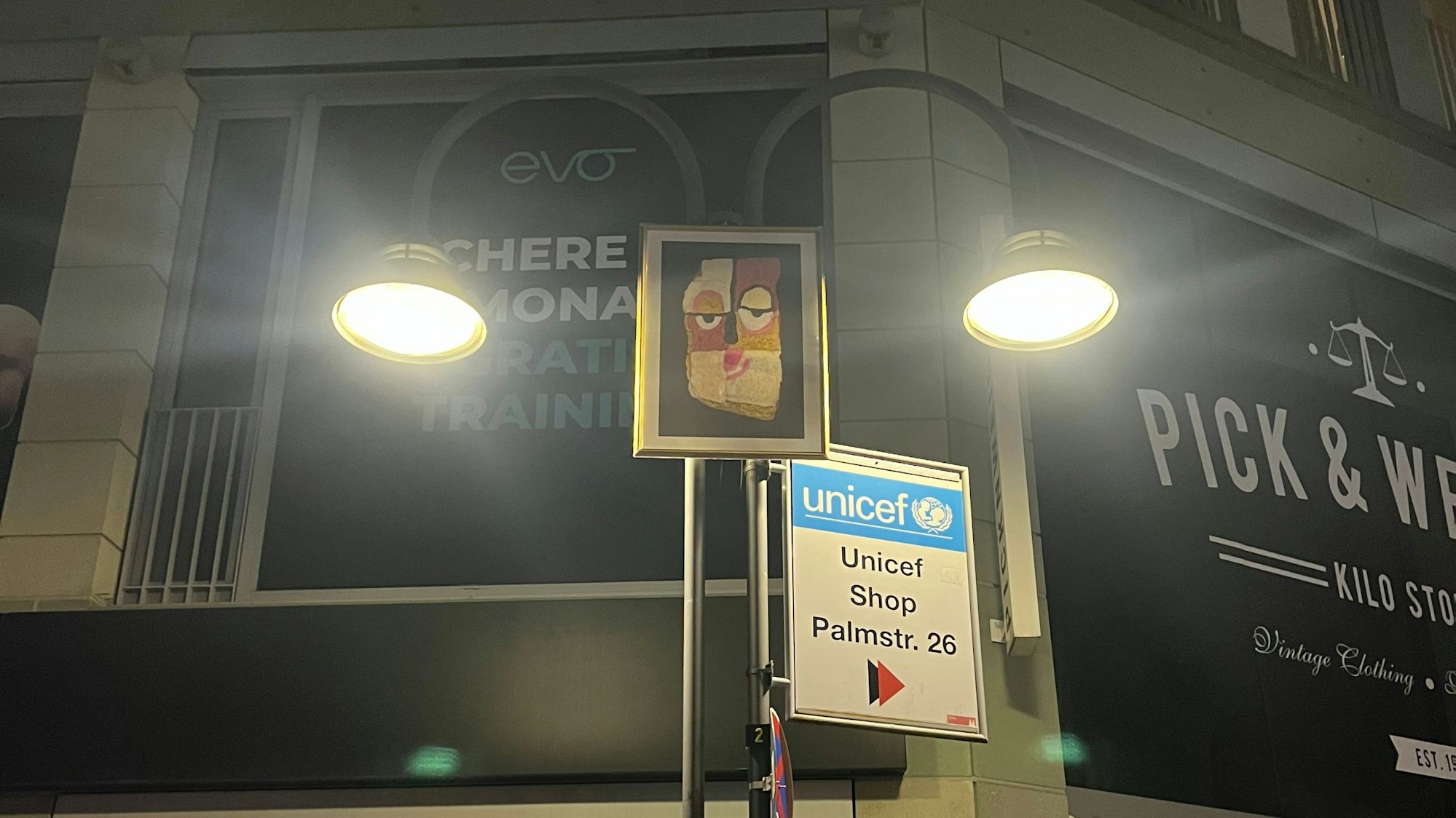 Lustige Gesichter an Laternenmasten in der Ehrenstraße, im Dunkel und von den Laternen angeleuchtet