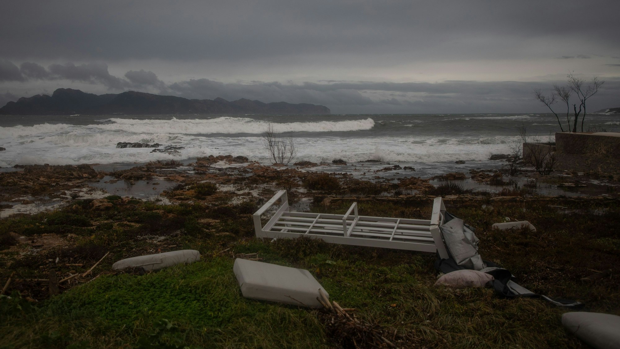 Vom Wind verwehte Möbel am Strand von Alcudia auf Mallorca bei stürmischem Wetter und starkem Seegang.
