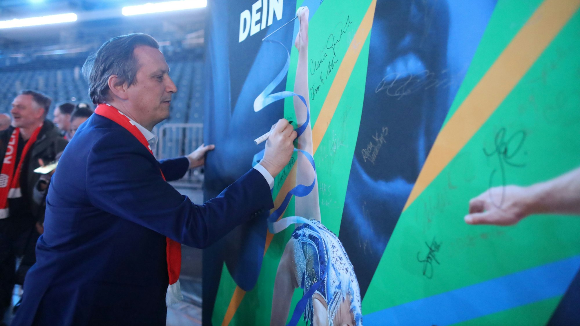 Beim Kampagnenstart der Köln-Rhein-Ruhr-Bewerbung zeigte Lionel Souque seine Unterstützung in der Lanxess-Arena. Auf dem Bild setzt er seine Unterschrift auf ein Werbeplakat
