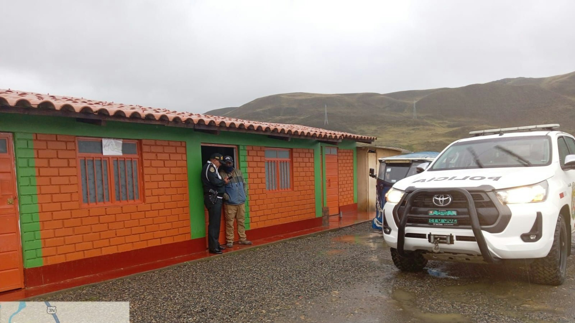 Das Bild zeigt ein Polizeifahrzeug und ein Haus in den Anden.
