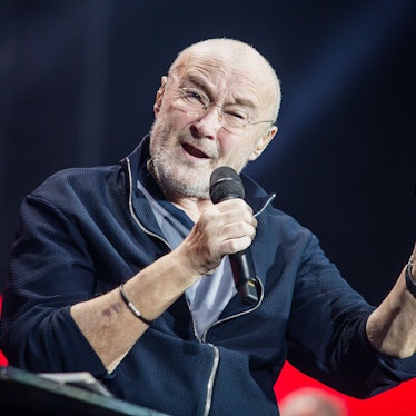 Sänger Phil Collins sitzt auf der Bühne und singt.