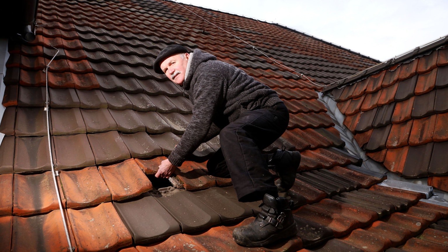 Dachdecker Bernhard Bartnik tauscht einen Ziegel aus.