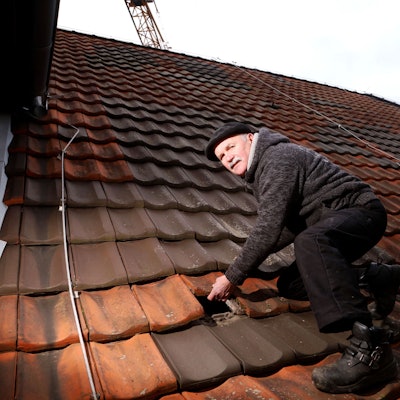 Dachdecker Bernhard Bartnik tauscht einen Ziegel aus.
