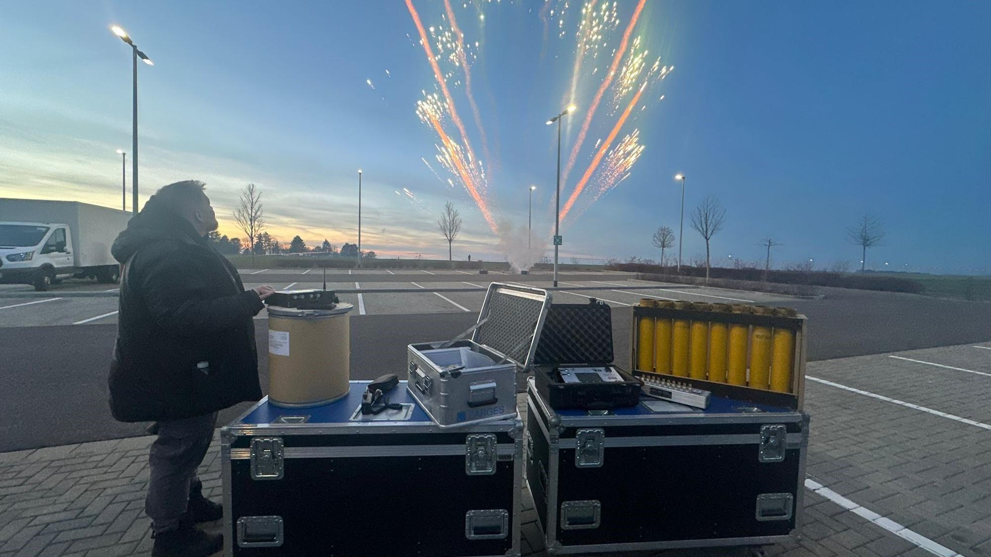 Das Bild zeigt einen Pyro-Techniker, der einen Feuerwerkskörper gezündet hat.