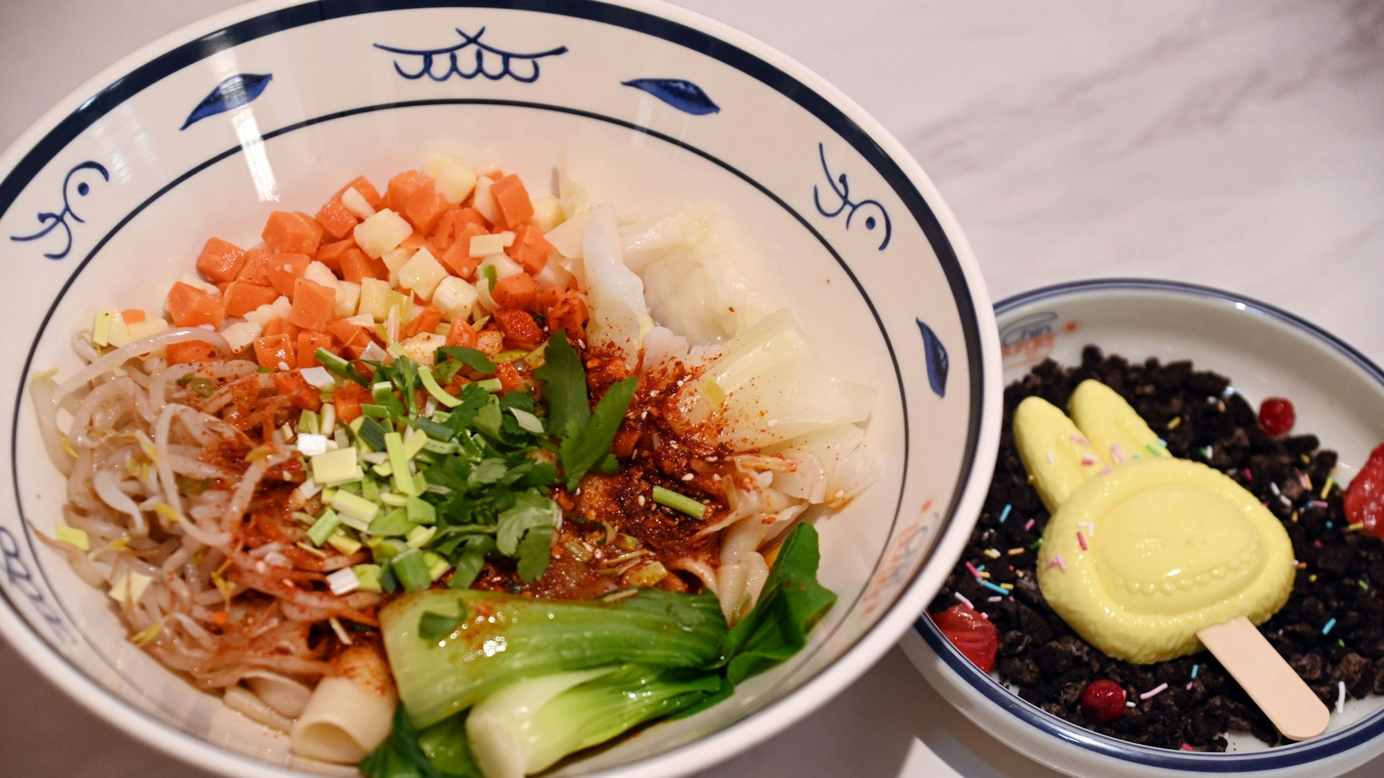 Zwei Schälchen mit Speisen sind zu sehen, eines davon das Dessert Labubu-Mousse in typischer Form mit langen Ohren.