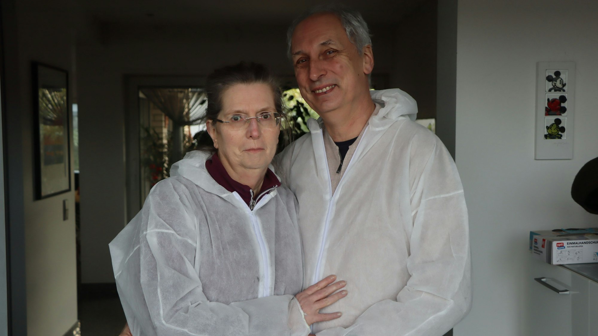 Ein Mann und eine Frau tragen weiße Schutzanzüge