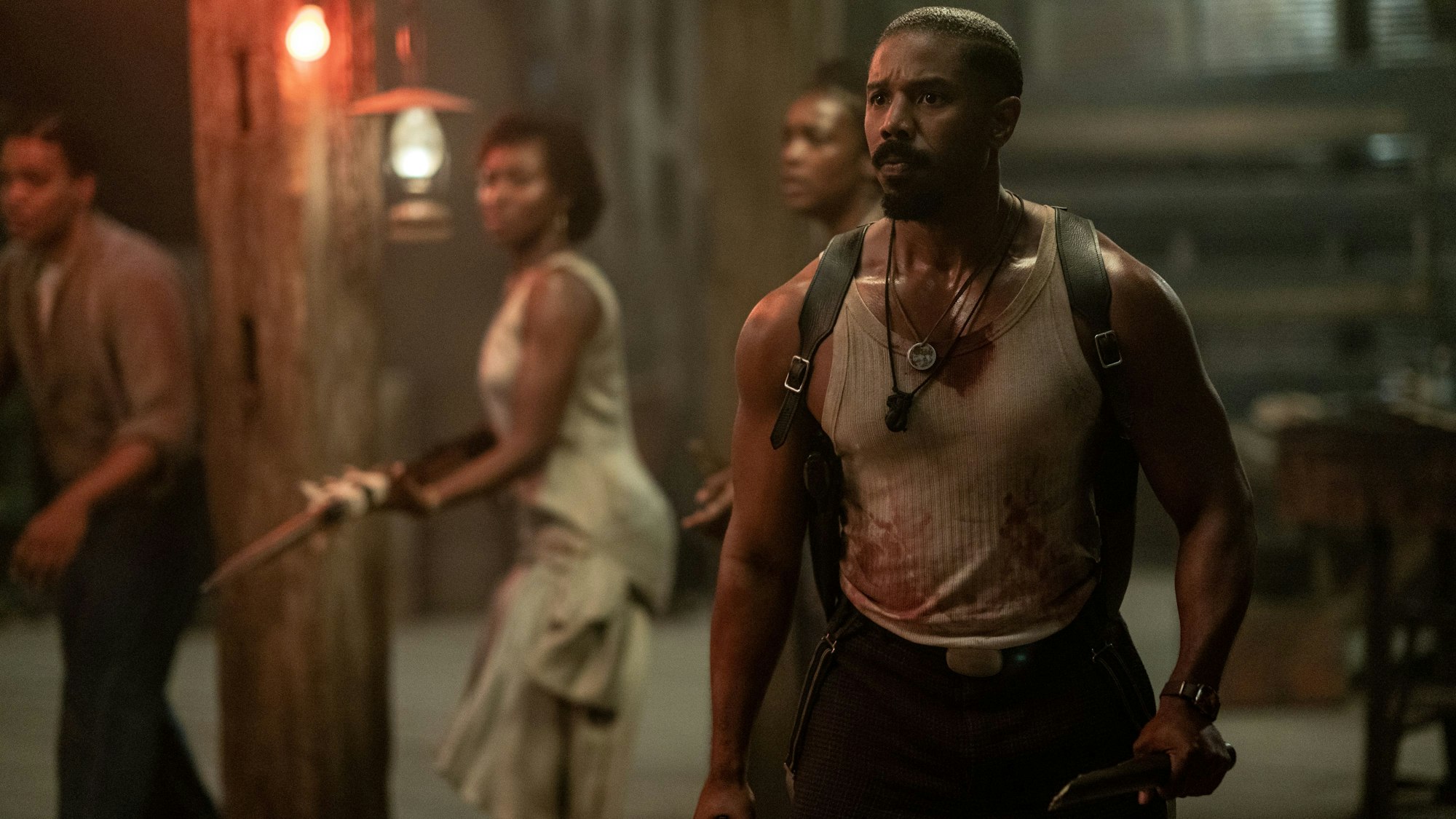 Michael B. Jordan steht mit blutigem Unterhemd und Messer in der Hand Vampiren gegenüber.