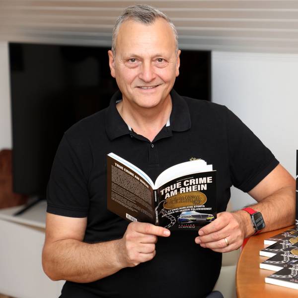 Polizist Bernhard Hatterscheidt steht neben einem Tresen und hält sein neues Buch in den Händen.