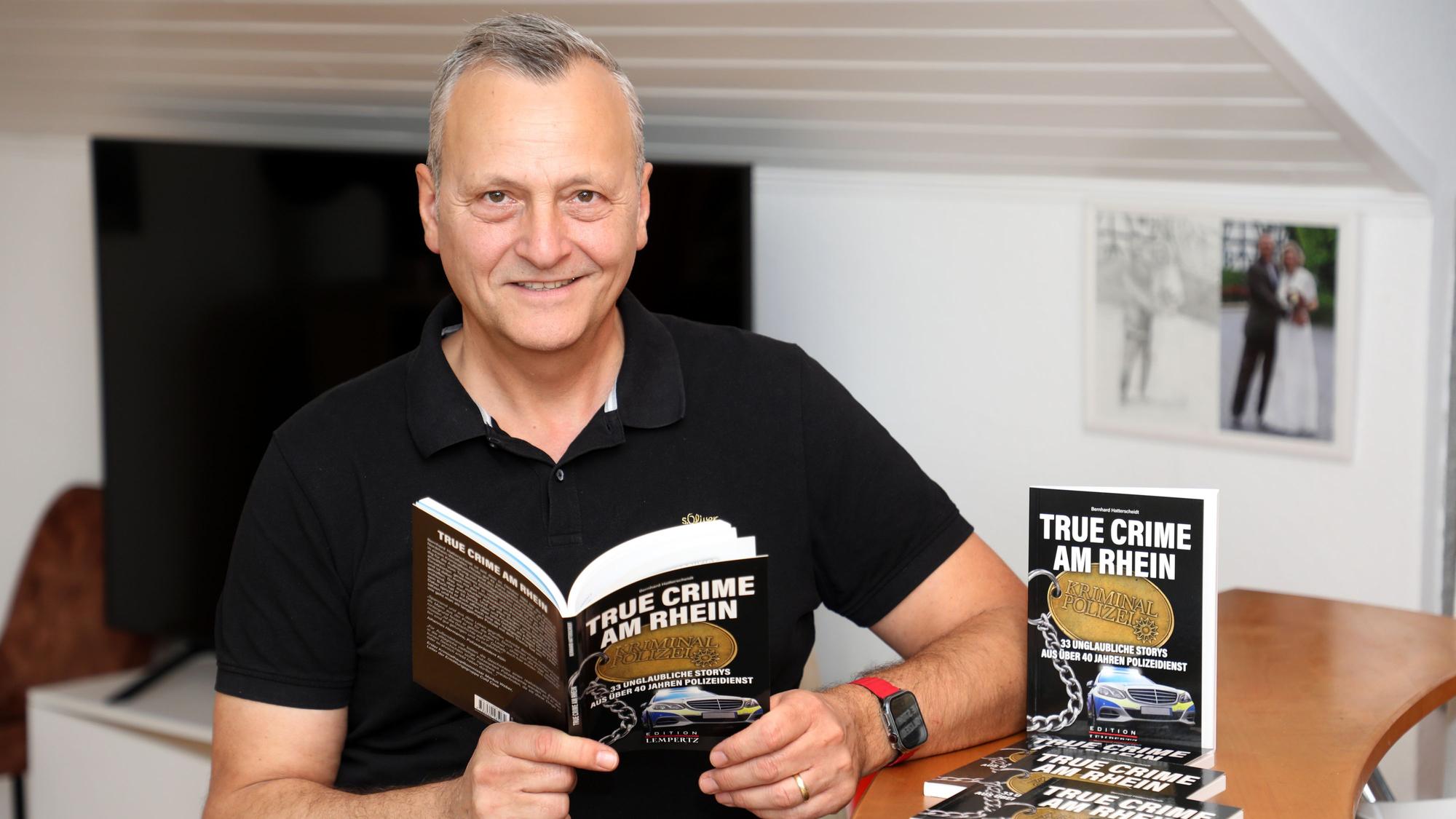 Polizist Bernhard Hatterscheidt steht neben einem Tresen und hält sein neues Buch in den Händen.