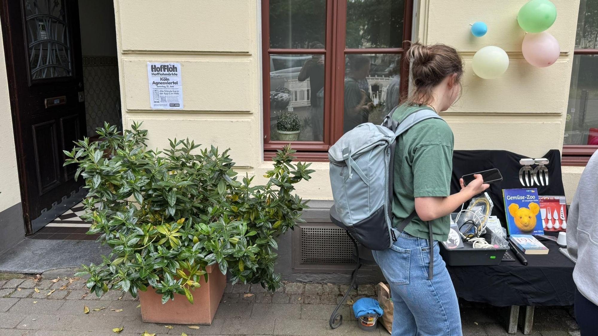 Eine Frau schaut sich einen Hofflohmarkt-Stand an.