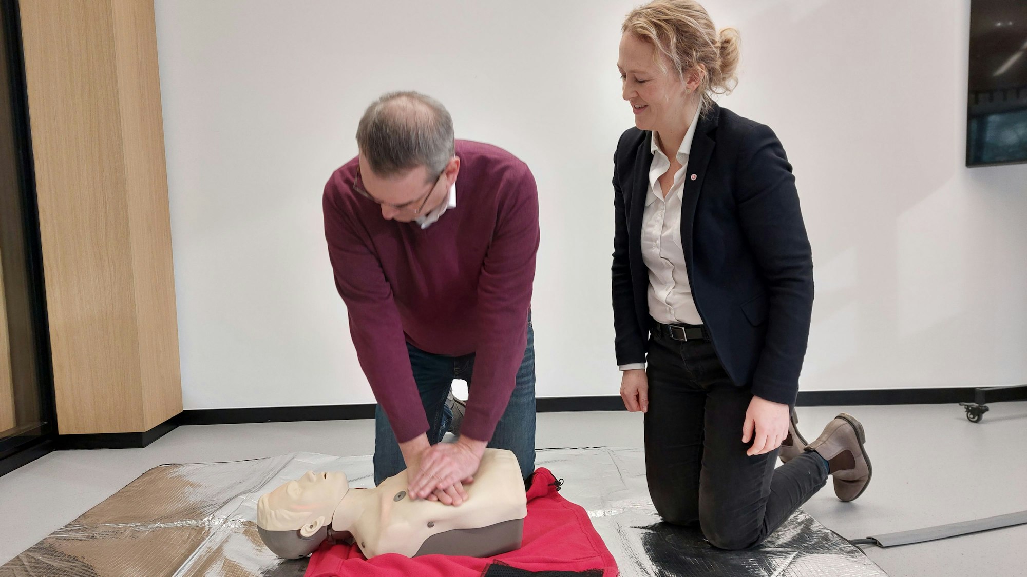 Ein Mann und eine Frau mit einer Übungspuppe für Herz-Lungen-Wiederbelebung.