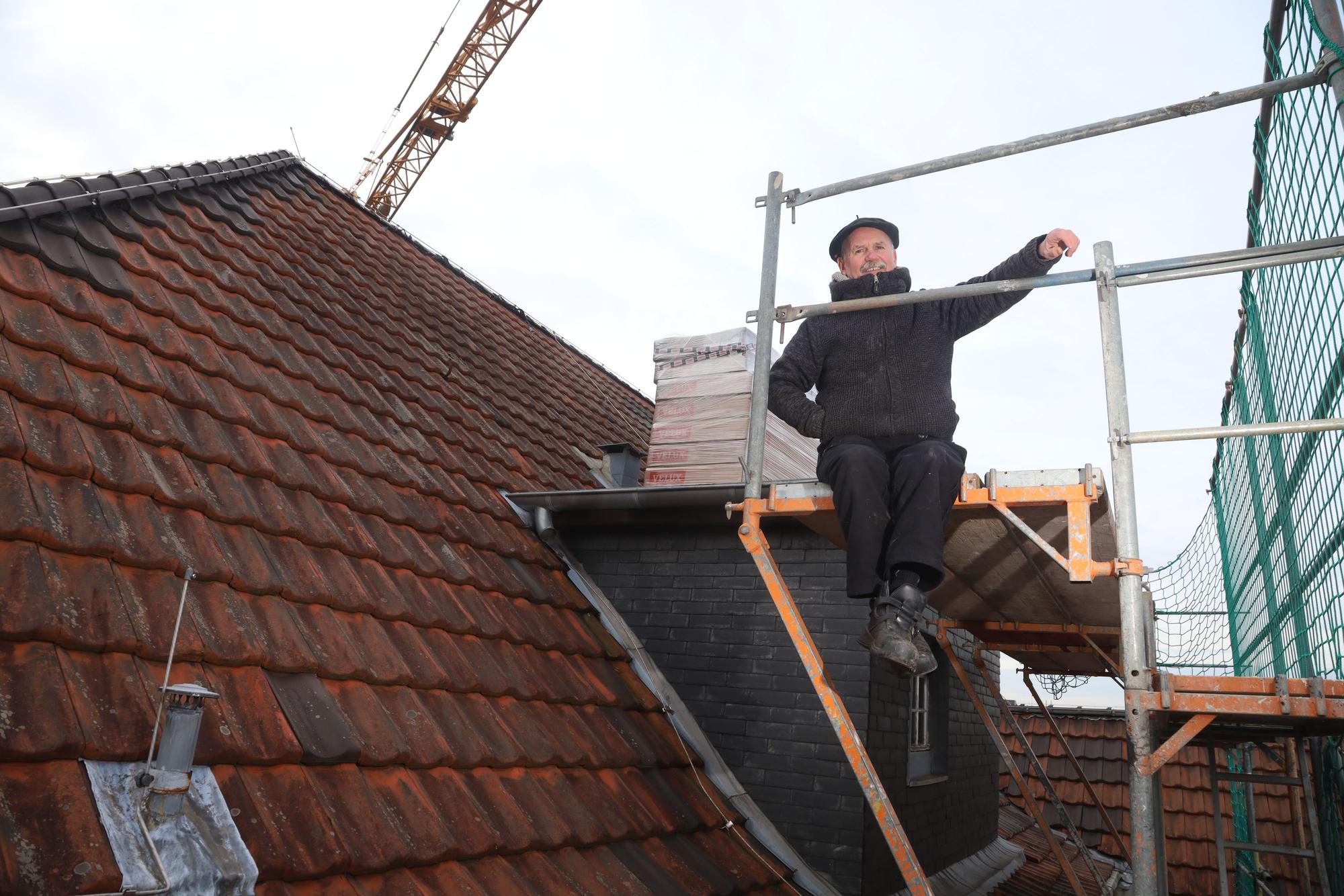 Bartnik Sitzt auf einer Gaube und lacht in die Kamera.