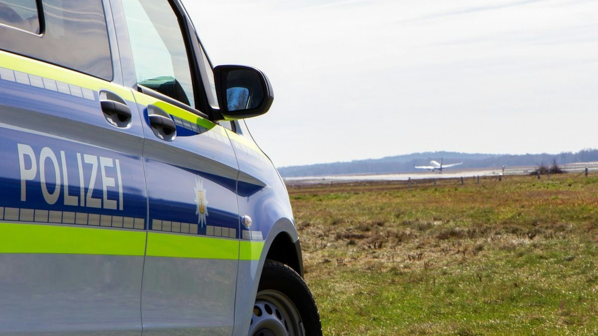 Ein startendes Flugzeug und ein Streifenwagen der Bundespolizei am Flughafen.