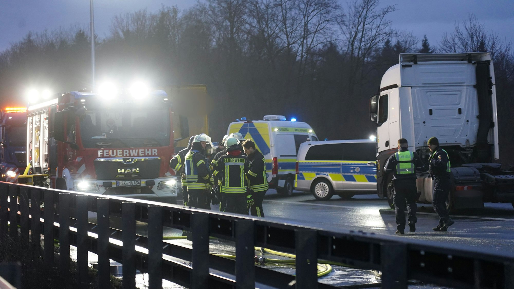 Feuerwehr und Polizei stehen auf der Fahrbahn nach einer durch Glätte ausgelösten Unfallserie mit mehreren Toten und vielen Verletzten auf der A44.