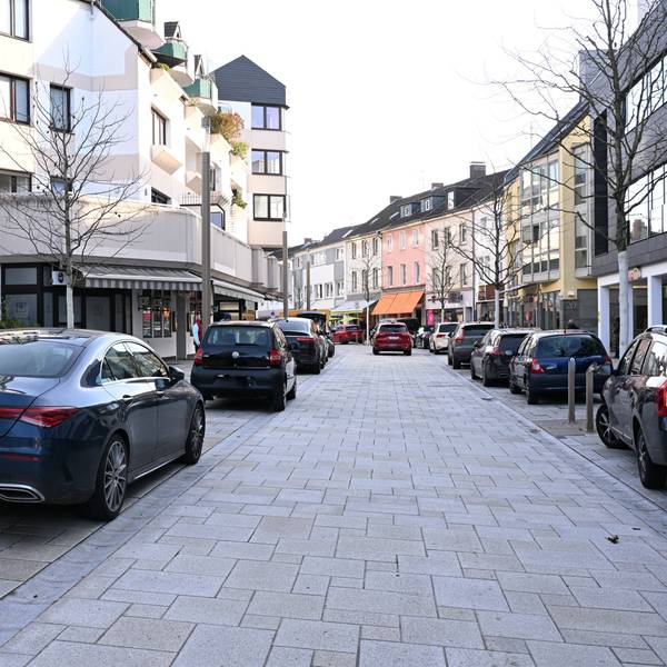 Rechts und links stehen Autos an der Straßenseite.