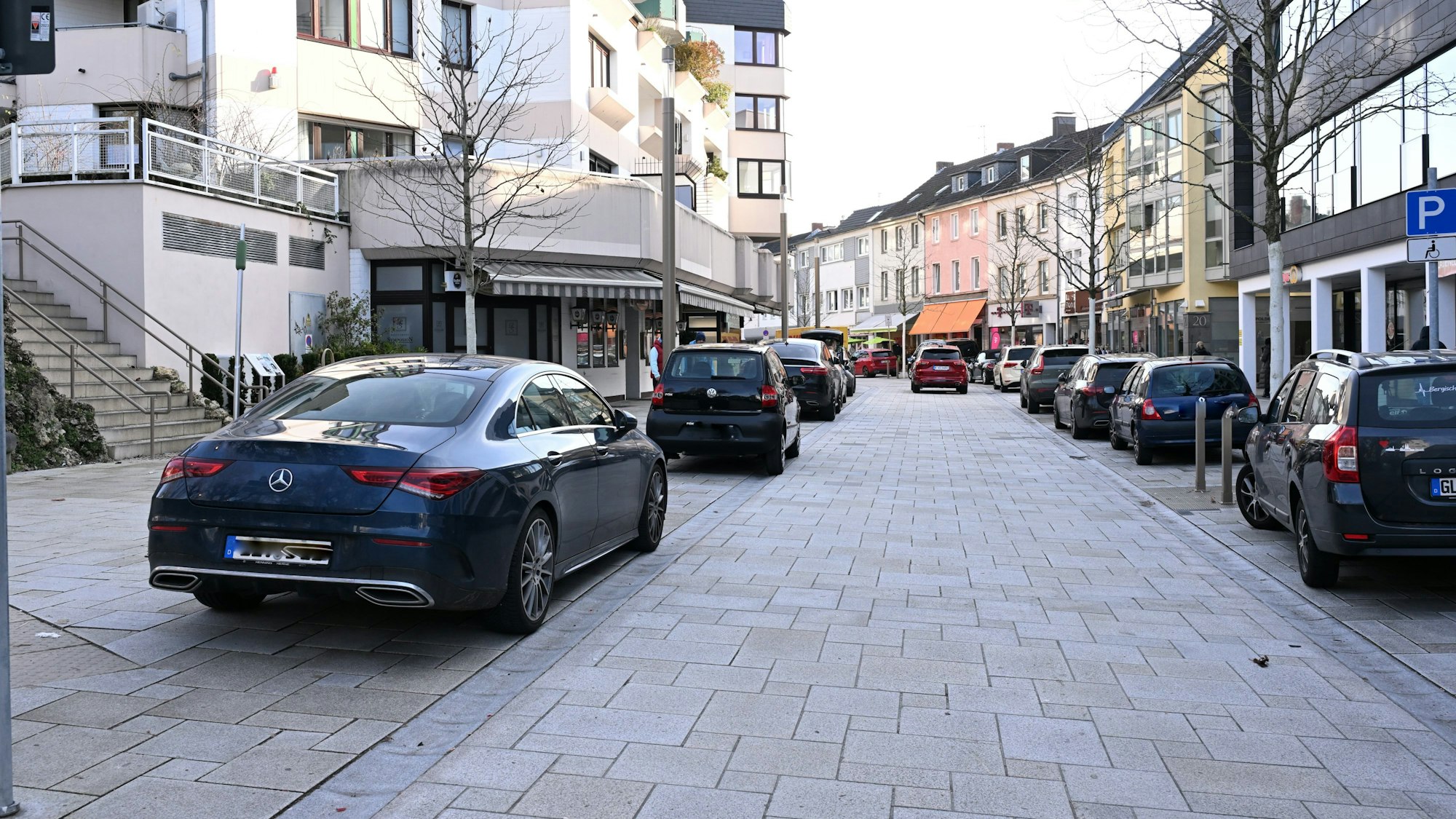 Rechts und links stehen Autos an der Straßenseite.