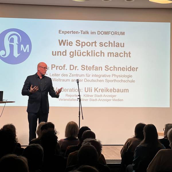 Ein Mann steht auf einer Bühne und gestikuliert.