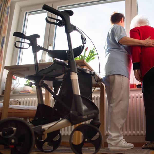 Das Bild zeigt eine Pflegerin mit einer Seniorin. Sie nimmt die ältere Frau in den Arm.
