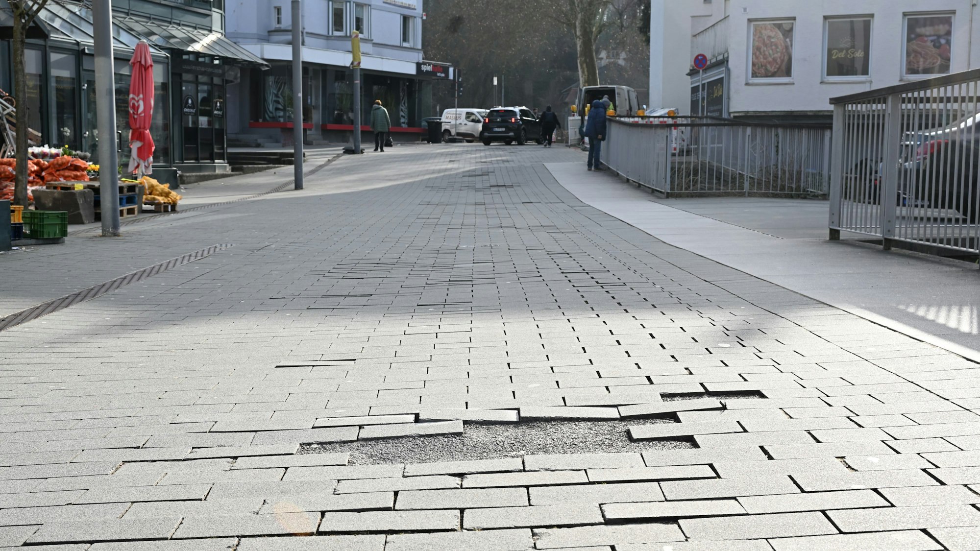 Zu sehen ist eine Straße mit herausstehenden Pflastersteinen.
