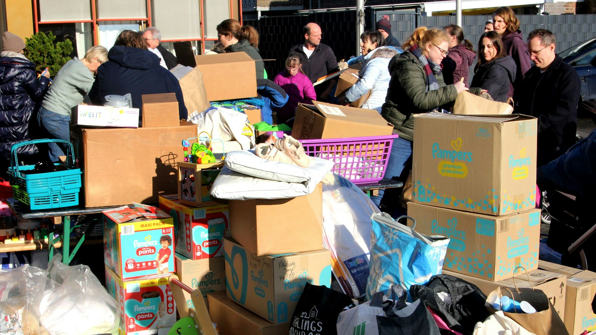 Kartons stapeln sich, dahinter stehen Menschen.