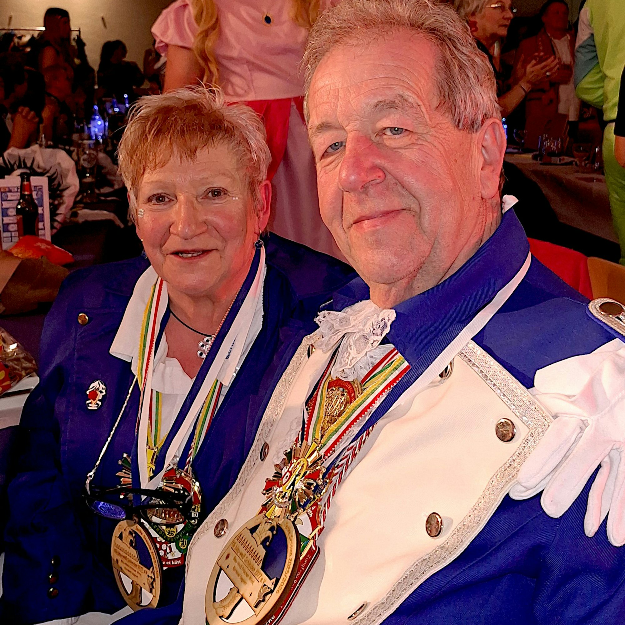 Adelheid und Norbert Niebes sitzen nebeneinder und tragen blaue Karnevals-Uniformen und Orden um den Hals.