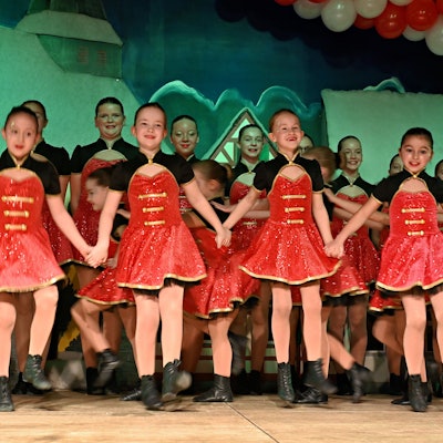 Viele Junge Tänzerinnen in roten Kostümen stehen auf der Bühne des Palmersheimer Dorfgemeinschaftshauses.