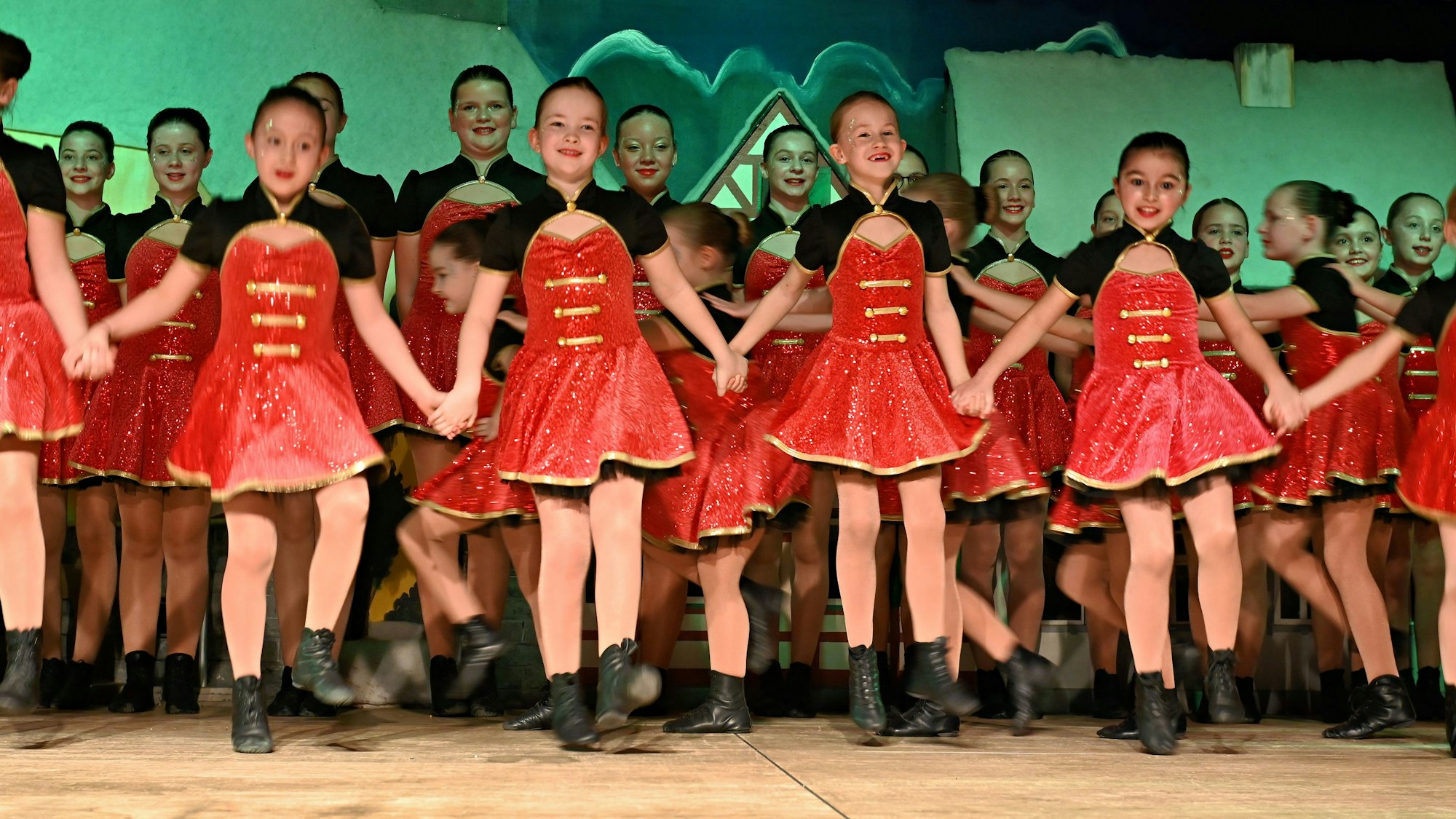 Viele Junge Tänzerinnen in roten Kostümen stehen auf der Bühne des Palmersheimer Dorfgemeinschaftshauses.