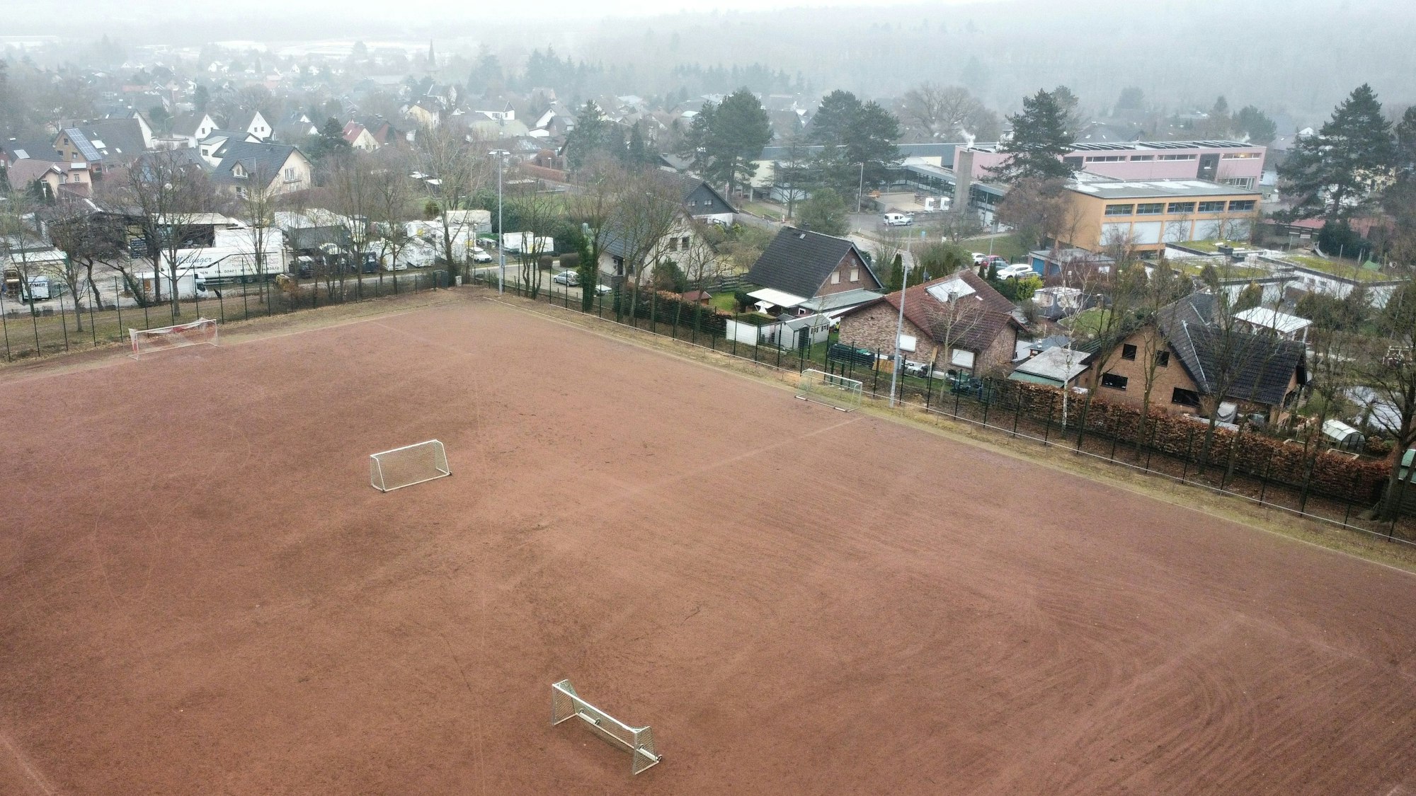 Drohnenaufnahme des Aschenplatzes in Satzvey mit Schule und Wohnbebauung im Hintergrund.