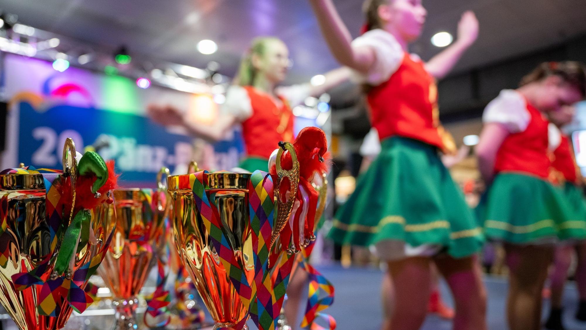 goldene Pokale des Pänz-Pokals mit Tanzgruppe im Hintergrund