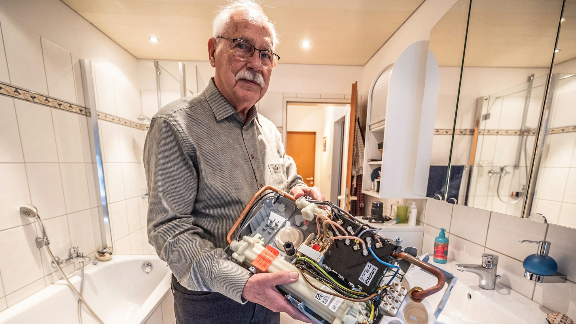 Harald Zander steht in seinem Bad mit dem defekten Durchlauferhitzer, dessen Elektronik am 11. Januar 2026 bei der mehrminütigen Überspannung abgeraucht war.