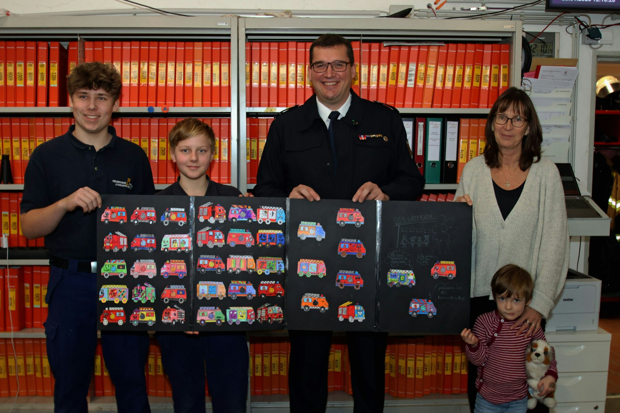 Auf dem Bild sind ein Mann, eine Frau und drei Kinder mit gemalten Feuerwehrautos zu sehen.