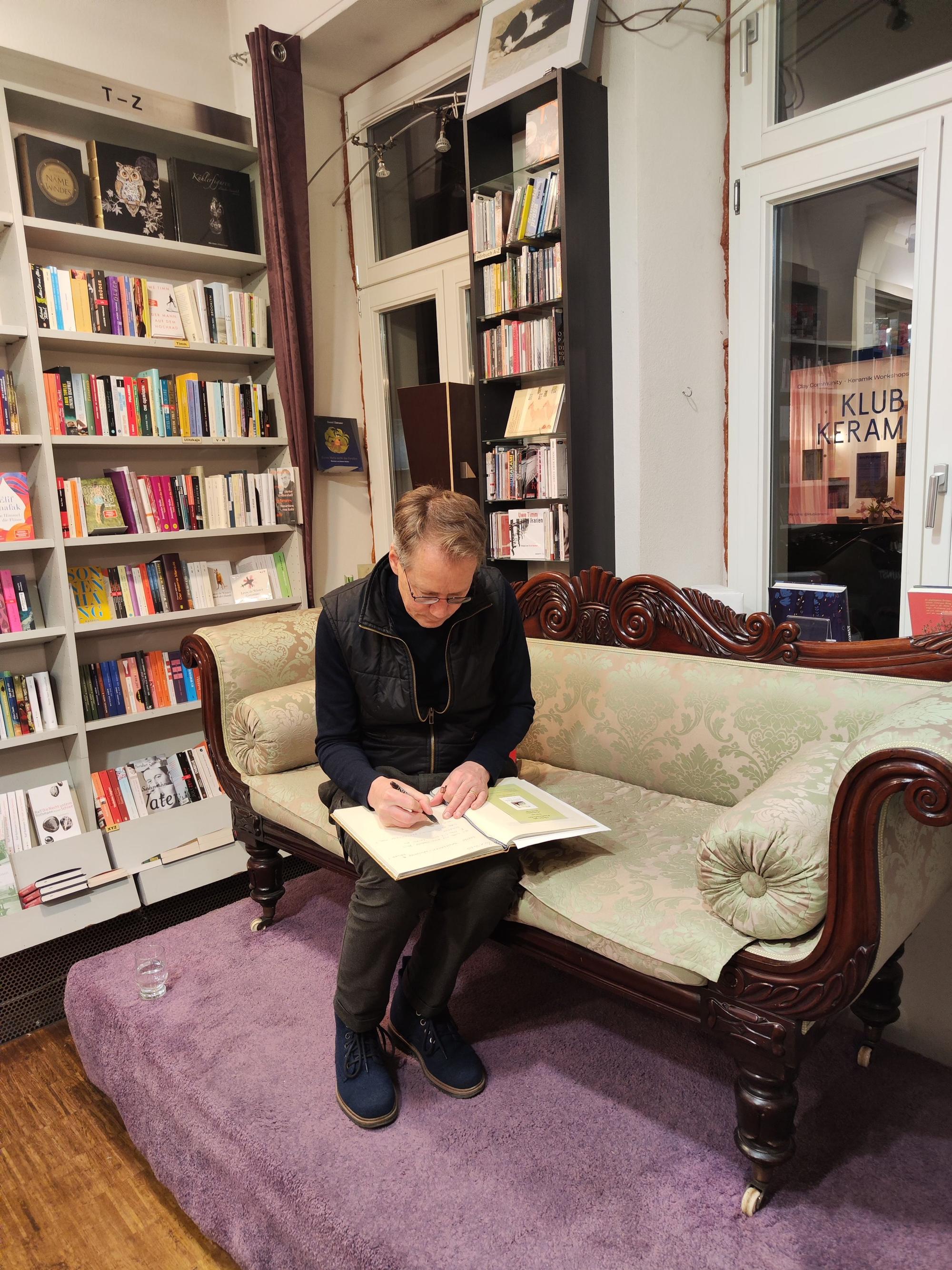 Ein Mann sitzt auf einem Sofa und schreibt in ein Buch.
