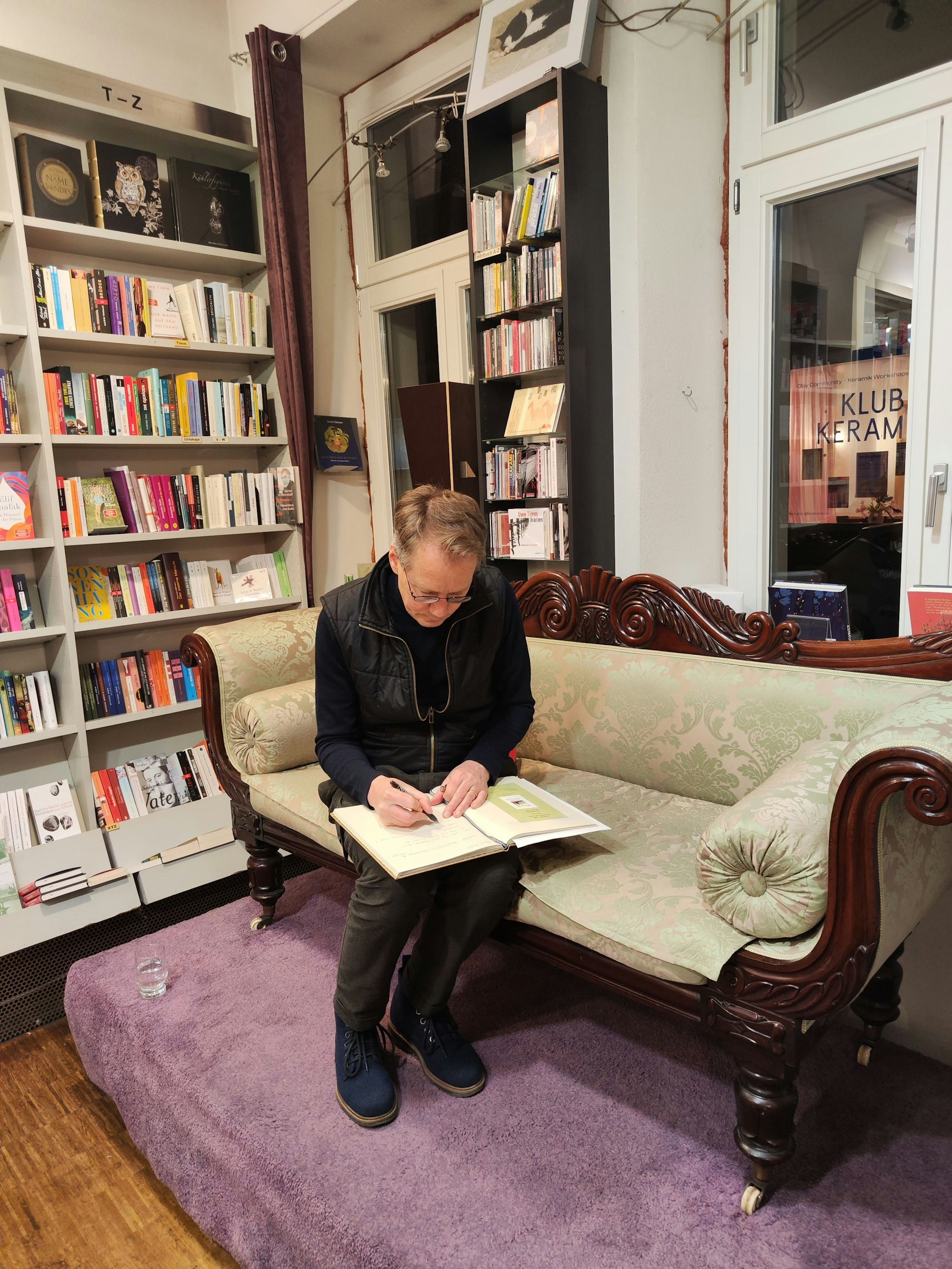 Ein Mann sitzt auf einem Sofa und schreibt in ein Buch.