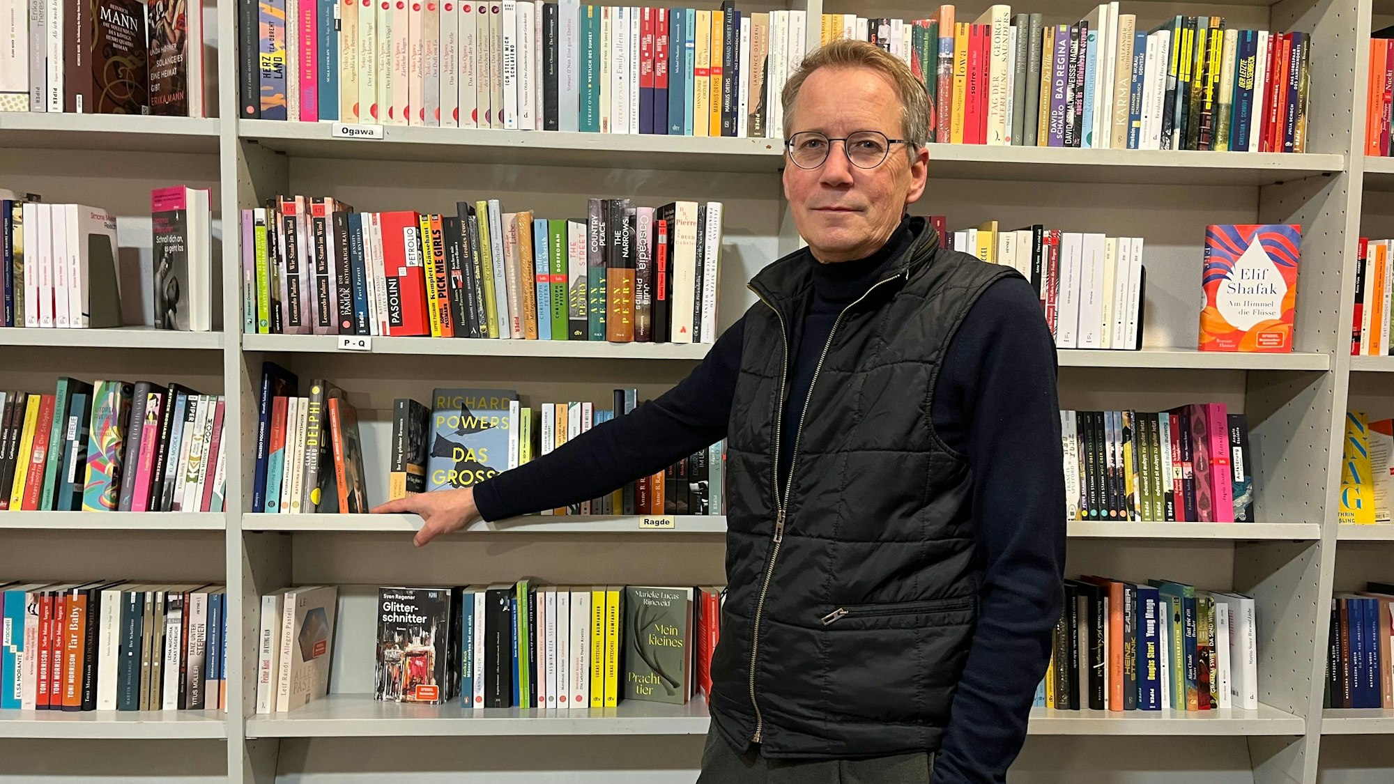 Mann steht vor Bücherregal