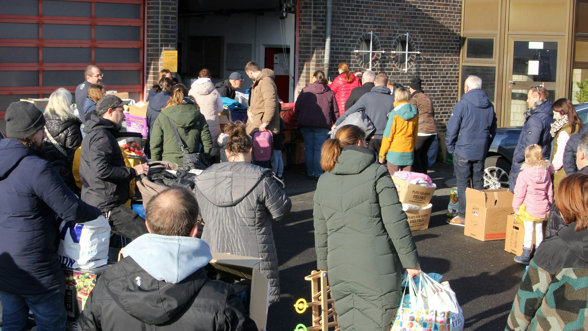 Auf dem Bild sind Menschen zu sehen, die Taschen und Kartons mit Spenden abgeben.